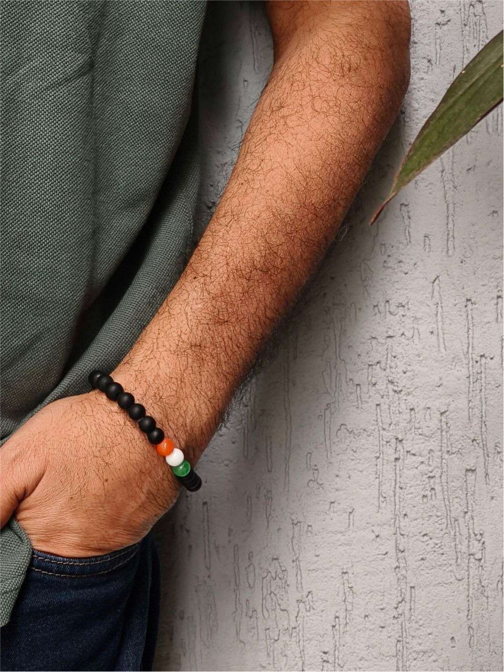A person's forearm wearing a black beads bracelet with three beads in the colors of the Indian flag.